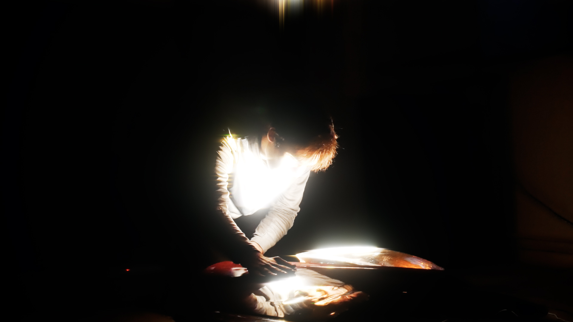 Performer leaning over illuminated car wreck parts.